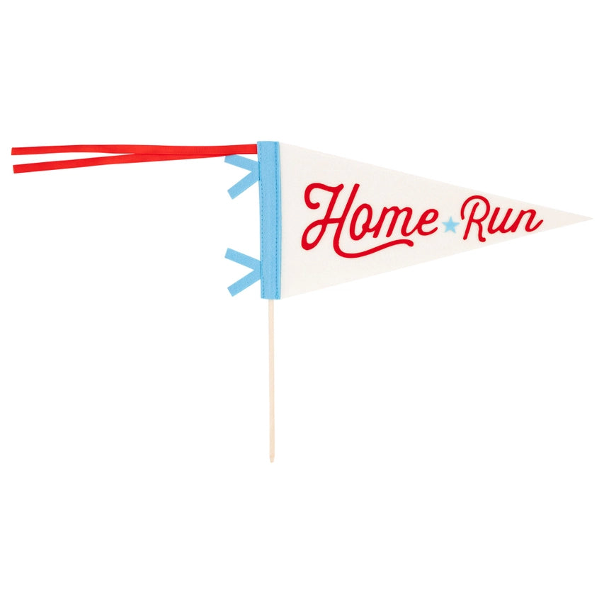 Isolated cream felt pennant with red “Home Run” script, blue trim, red ribbon tails, and attached wooden dowel on a white backdrop.