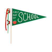 Isolated image of green felt “First Day of School” pennant with stitched text and red apple illustration