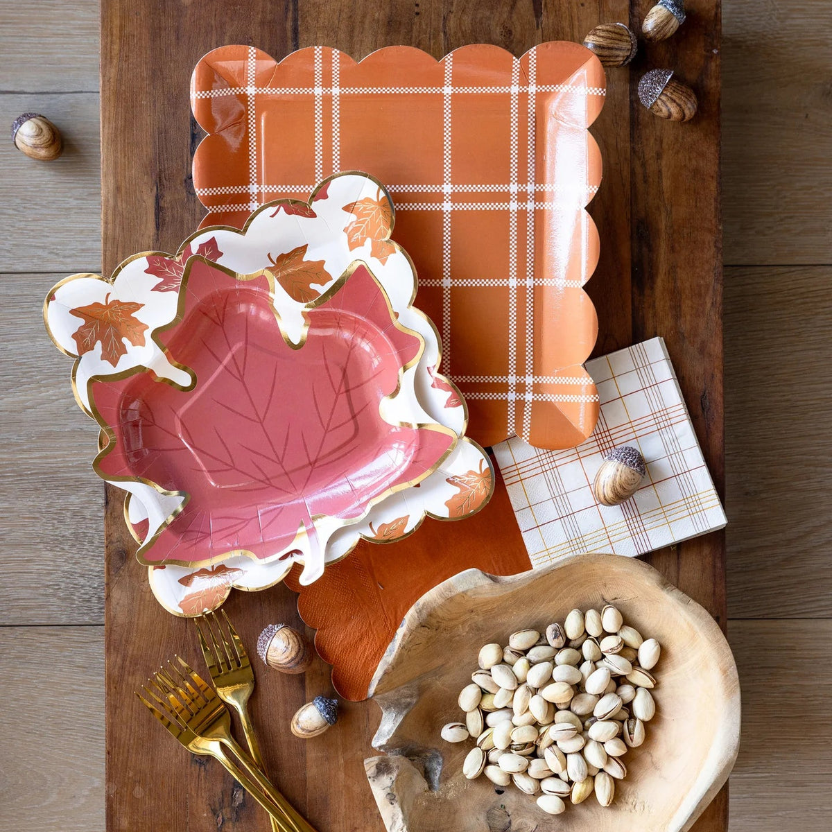 Plates styled on a fall tablescape with plaid tray, acorns, and nuts.