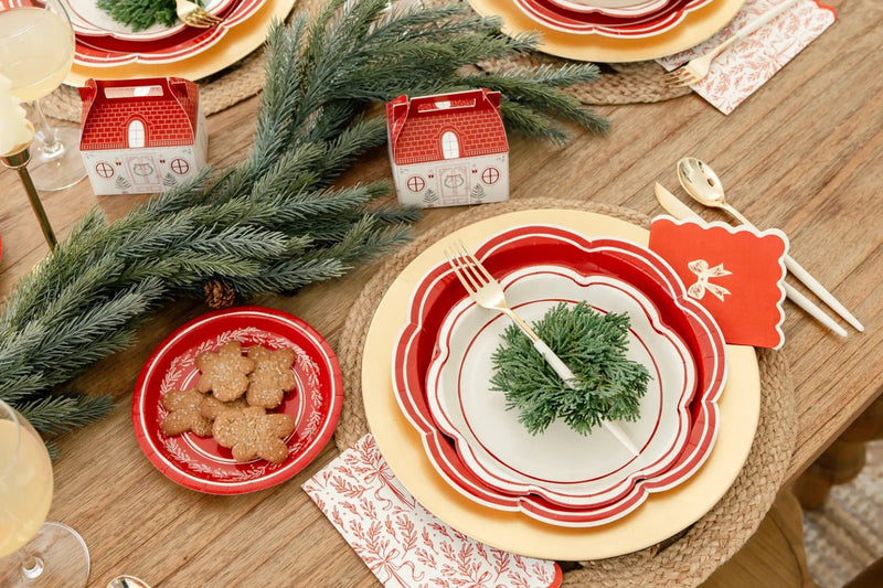 Close-up Christmas tablescape featuring red scalloped plates, cookies, and garland