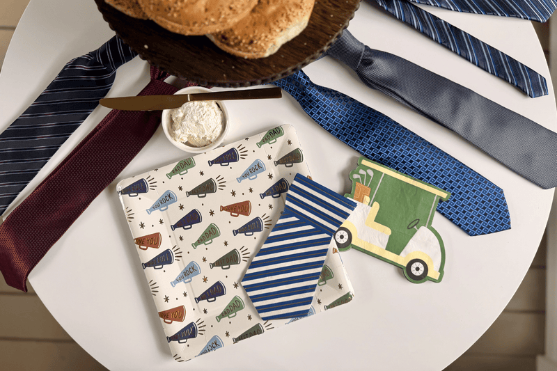 Father's Day table spread featuring square patterned paper plates, tie shaped napkins, and golf cart shaped napkins.