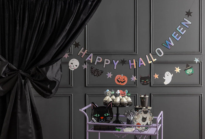 Both banners hung across a dark gray paneled wall above a Halloween party treat station with black curtains, white balloon garland, and ghost decorations.