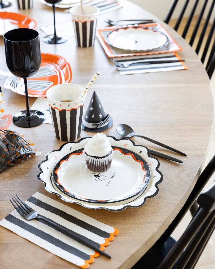 Halloween dinner napkins styled on a Halloween place setting with matching cups and straws.