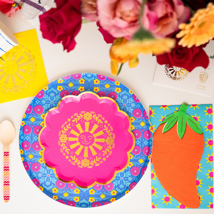 This image shows a colorful taco party table with floral plates, sun napkins, flowers, and fiesta decorations.