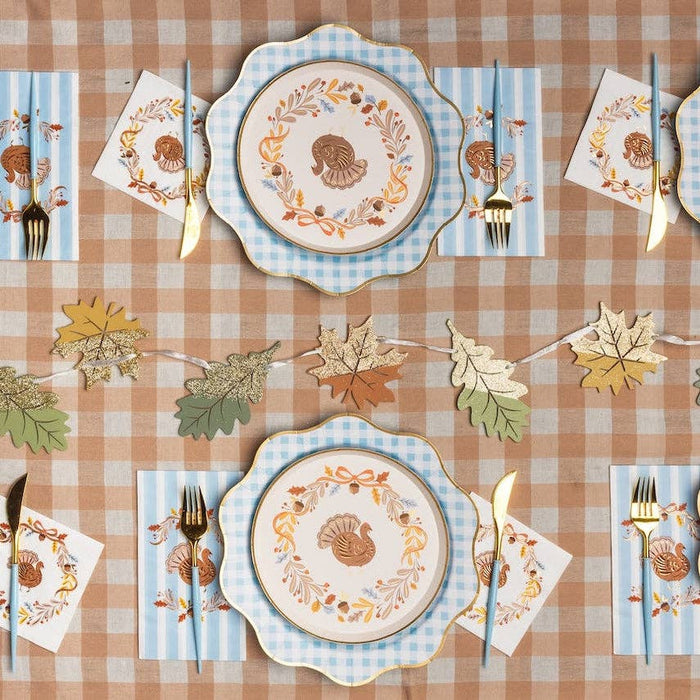 Preppy Thanksgiving table with turkey guest towels, turkey plates, gingham chargers and gold leaf garland