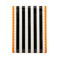 Flat view of the Orange and Black Striped Paper Table Runner showing black and white stripes with orange scalloped edges.
