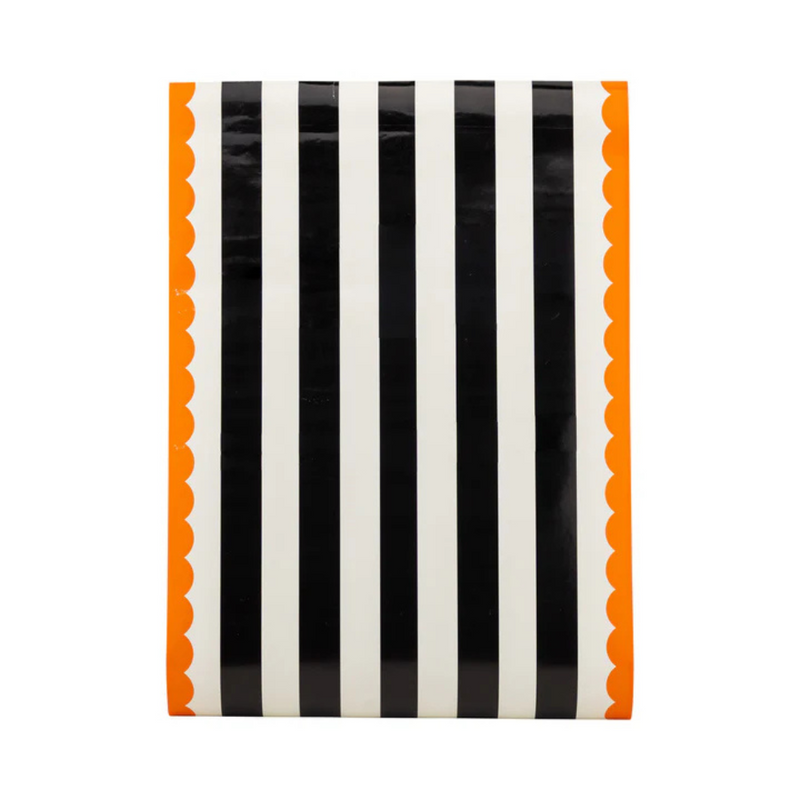 Flat view of the Orange and Black Striped Paper Table Runner showing black and white stripes with orange scalloped edges.