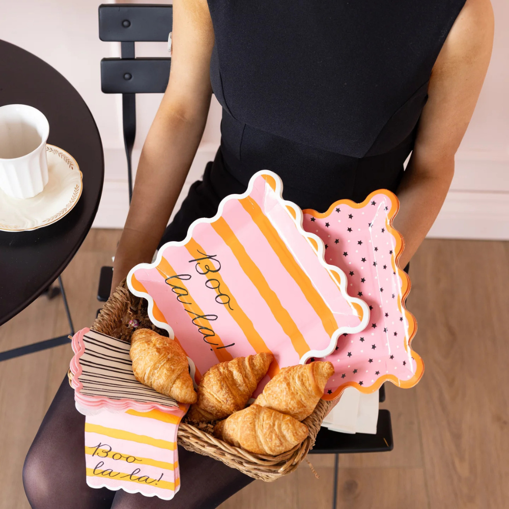 Person holding a basket of croissants with decorative signs in a casual setting.