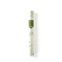 Adventure-themed paper table runner rolled in its packaging, with forest sketch peeking through and a green label showing dimensions and theme.