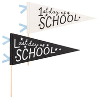 Flat lay of both 1st Day of School and Last Day of School felt pennants side by side on a white background showing cream and black colorways with wooden dowels