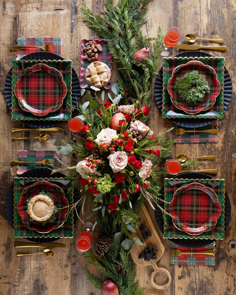 Christmas table setup with green plaid napkins, red plaid plates, and floral centerpiece
