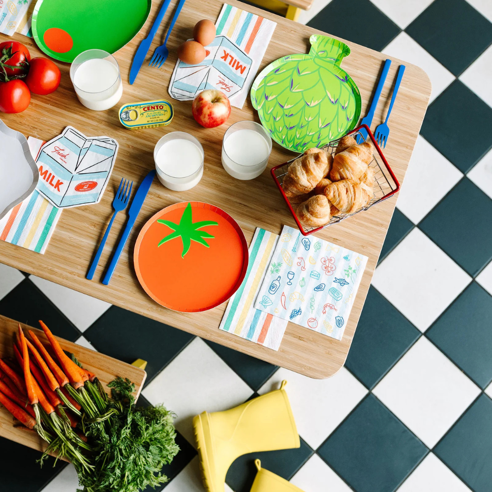 Styled table with Le Dinner Large Napkins, tomato plates, and vegetable-themed decor.