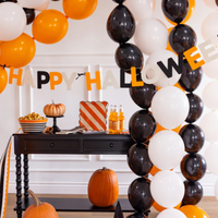 Felt & Bows Happy Halloween Banner displayed against a white wall with pumpkins, snacks, and orange soda bottles beneath.