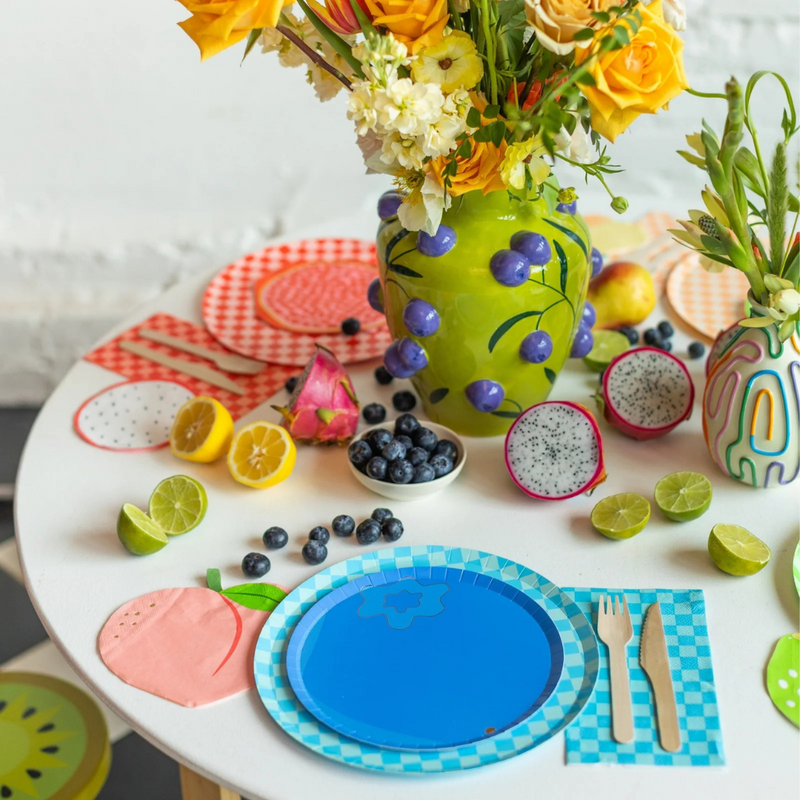 Close-up of peach-shaped napkin with gold foil accents next to blue checkered plate.