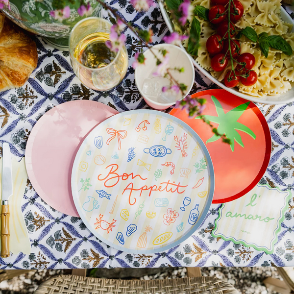 Outdoor table with pasta, tomatoes, and Le Dinner Bon Appetit Dinner Plate with colorful food illustrations.