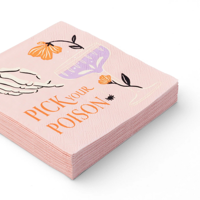 Close-up of stacked pink cocktail napkins with skeleton hand, florals, spider, and “Pick Your Poison” text.