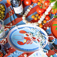 Festive seafood tablescape with Le Dinner Lobster Platter Charger Plate and tomato accents.