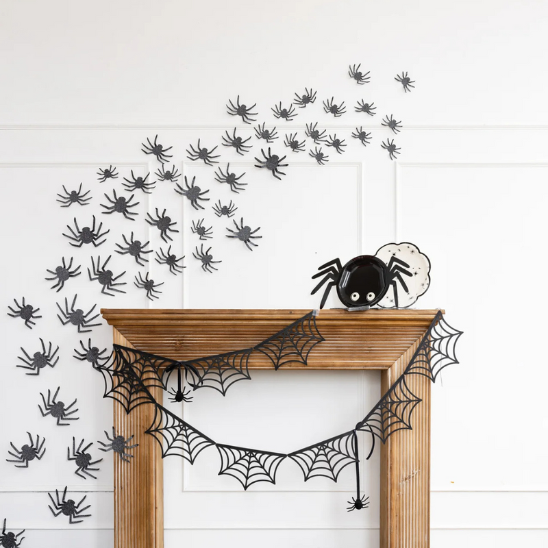 Halloween-themed mantel display with spider wall décor and spooky accents.
