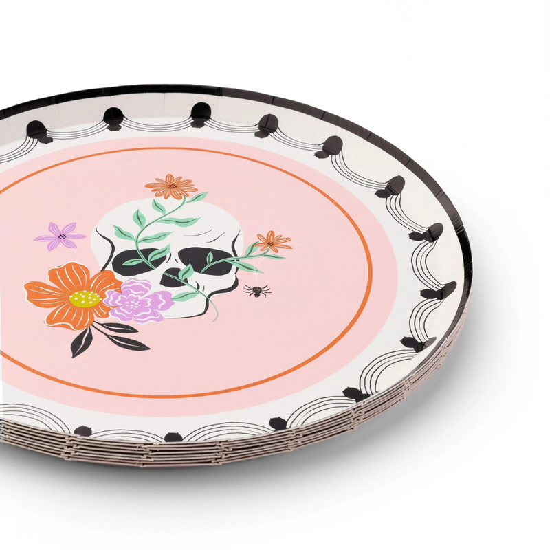 Stack of plates showing detailed skull and floral design against pastel pink background.