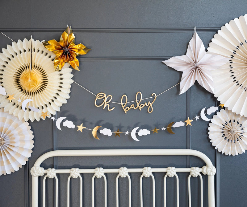 Oh Baby baby shower banner hanging above crib with gold foil lettering and celestial accents