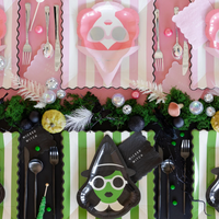 Green and pink-themed party table with Bad Witch and Good Witch place settings