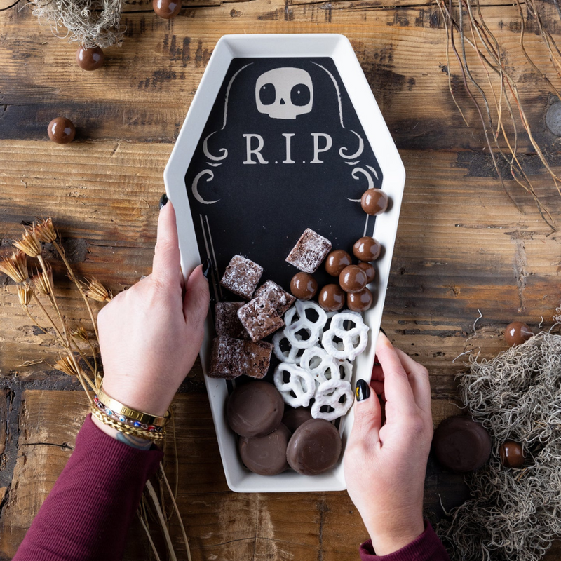 Top-down view of coffin tray on wood table with candy and pretzels