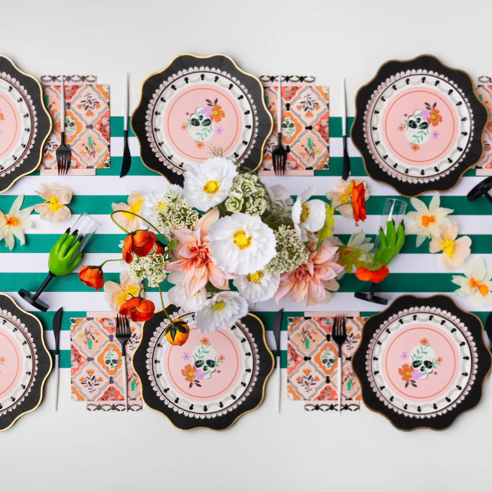 Styled Halloween table setting with Floral Skulls & Spiders dinner napkins, black plates, and floral centerpieces.