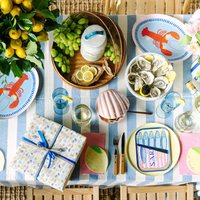 A styled party table with Le Dinner Lemon Cocktail Napkins under plates.