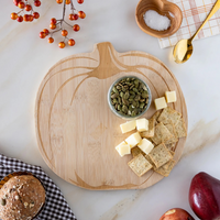 Styled table with pumpkin wood cutting board holding cheese, crackers, and pumpkin seeds.