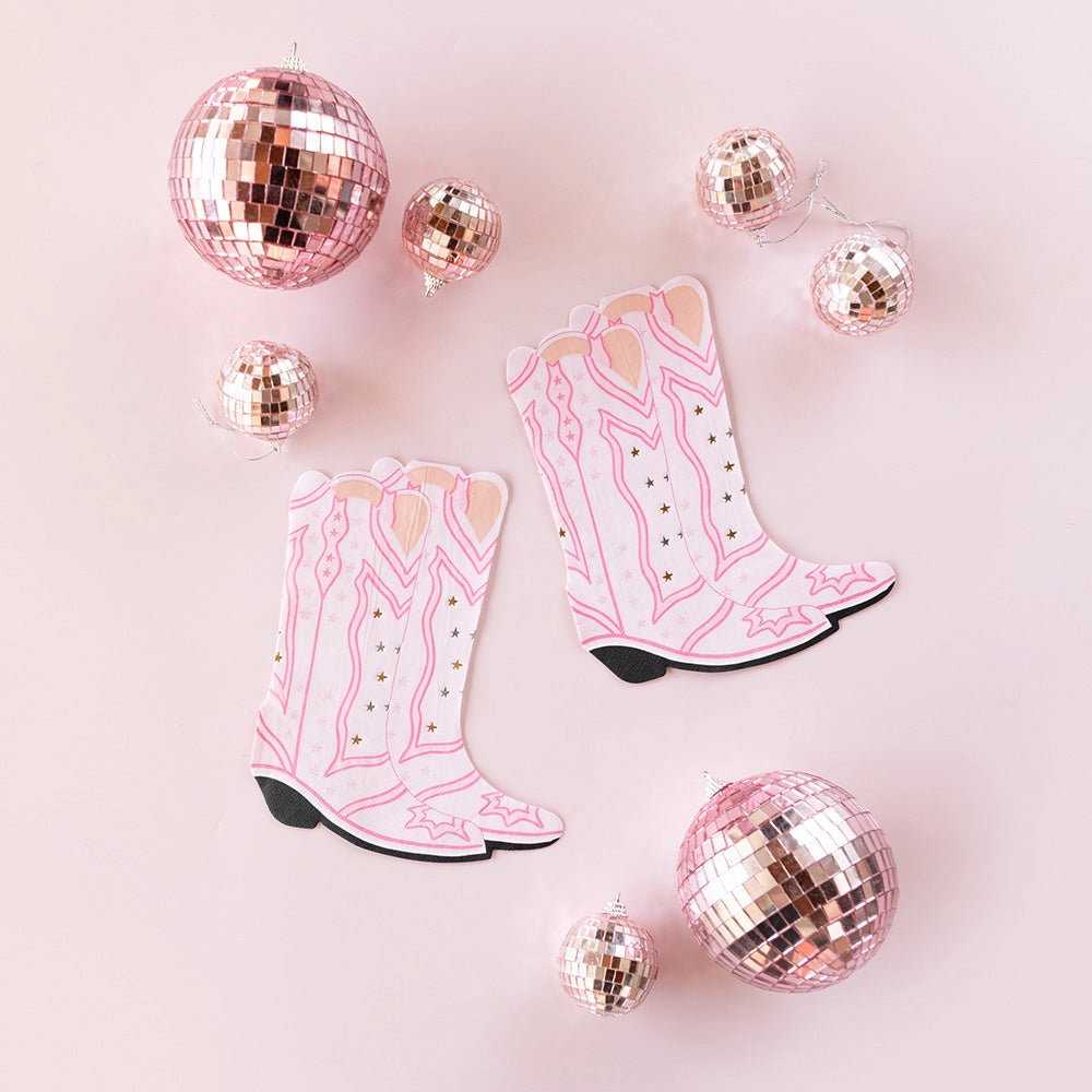 Two pairs of pink cowgirl boot napkins and three rose-gold disco balls placed on a blush-pink surface—ready to adorn a little cowgirl’s table.