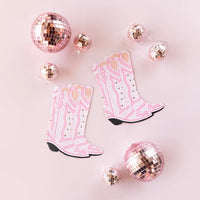 Two pairs of pink cowgirl boot napkins and three rose-gold disco balls placed on a blush-pink surface—ready to adorn a little cowgirl’s table.