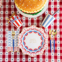 A set of 4th of July guest towels styled with blue and white striped cups, gold flatware, and a red gingham tablecloth, creating the perfect patriotic party setup.