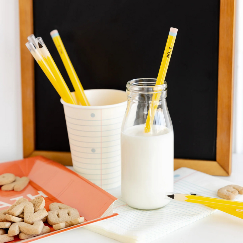Styled party setup with milk, alphabet cookies, and pencil straws in paper cups