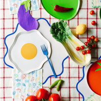 Le Dinner table setting with napkins, plates, and fresh produce decor.