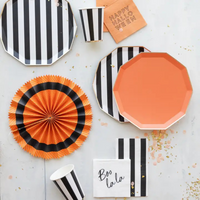 Overhead flat lay of a Halloween party setup featuring striped tableware, orange napkins reading “Happy Halloween,” and festive decorations.