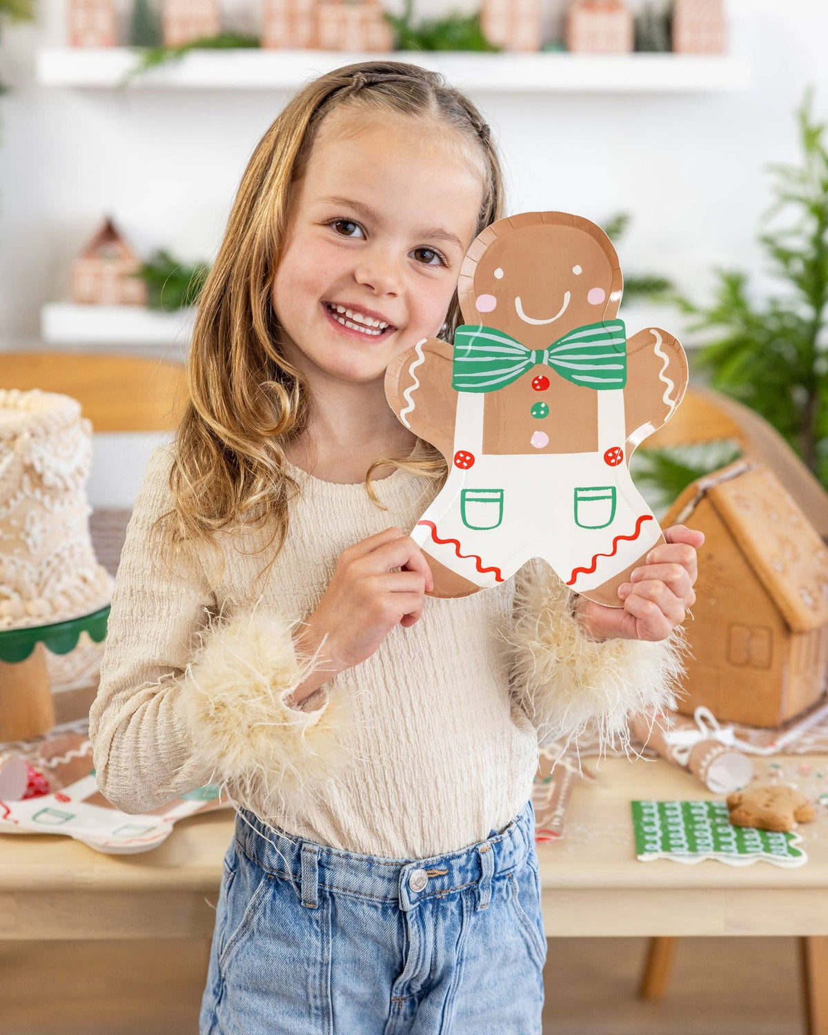 Another view of the child posing with the Gingerbread Man Plate at a festive table.