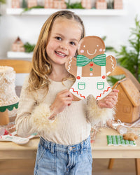 Another view of the child posing with the Gingerbread Man Plate at a festive table.