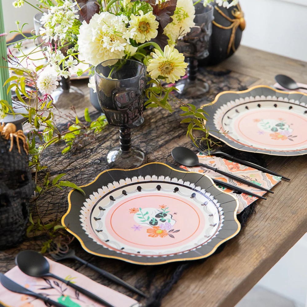 Elegant Halloween dinner party setup featuring floral skull napkins and black skull goblets.
