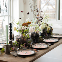 Side view of an elegant Halloween tablescape with dessert plates, skull decorations, and flowers.