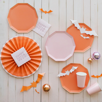 Flat lay of Happy Halloween Pink Cocktail Napkins styled with orange and pink plates, bat cutouts, and pastel décor.