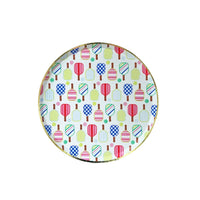 Isolated round dessert plate featuring multicolor pickleball paddles and balls with gold foil rim on white background.