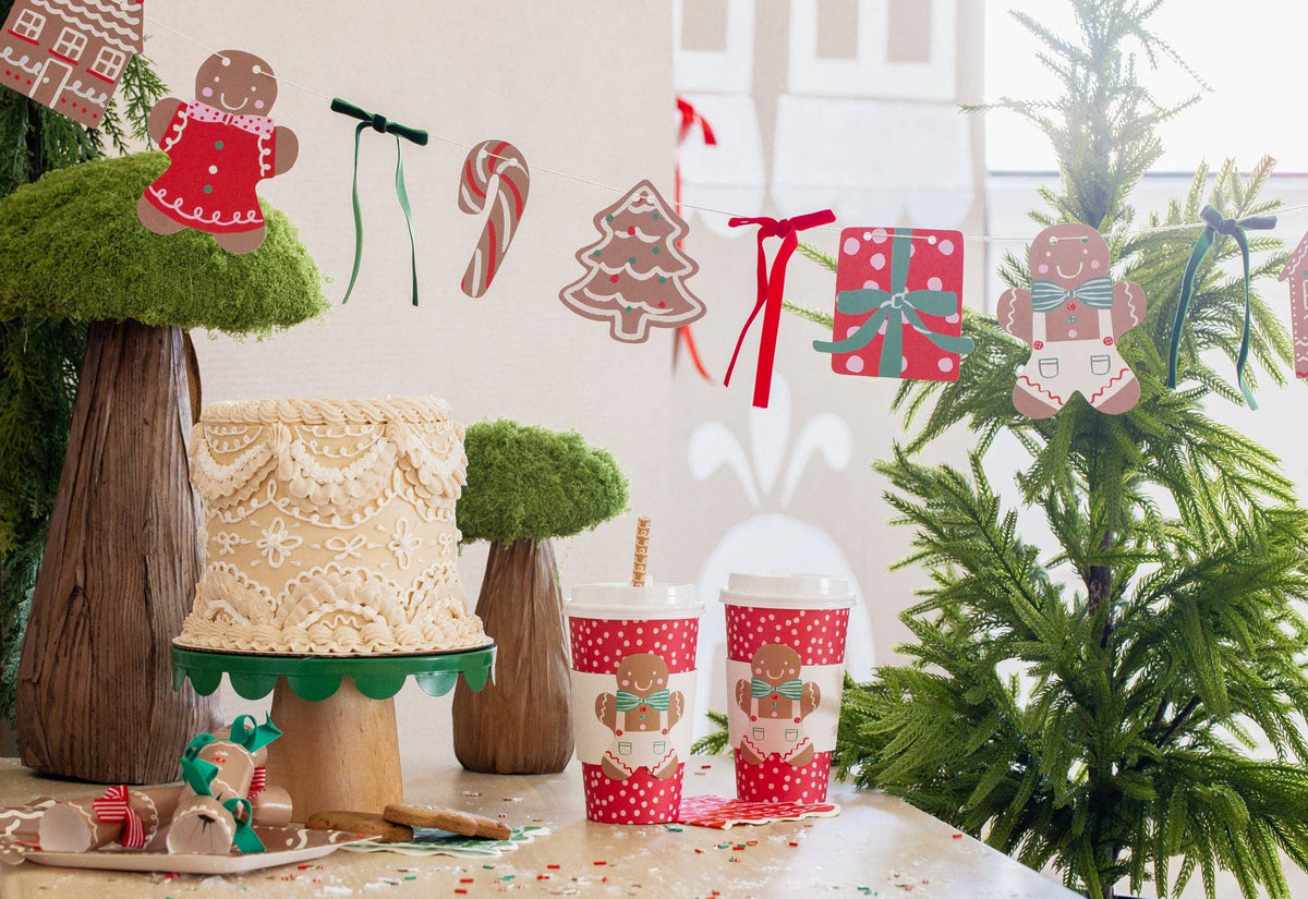 Christmas tablescape featuring Gingerbread To-Go Cups and gingerbread banner with different Christmas-themed shapes and ribbons