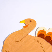 Close-up of a turkey napkin showcasing the turkey's face and detailed feathers. These Thanksgiving paper napkins combine charm with functionality for your holiday celebrations.