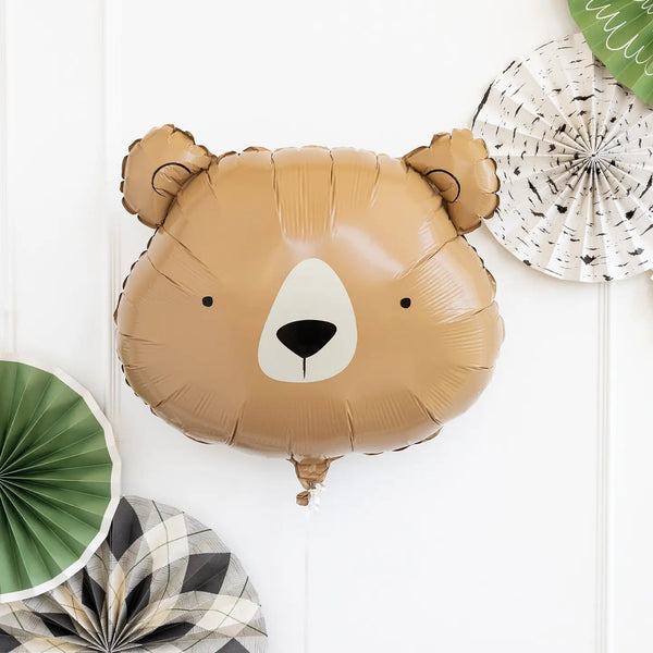 Inflated bear head mylar balloon hanging on a white wall with green and neutral rosettes, perfect for a camping birthday party.