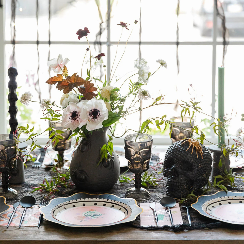 Close-up of one dessert plate on a Halloween table with black cutlery and spooky spider web accents.