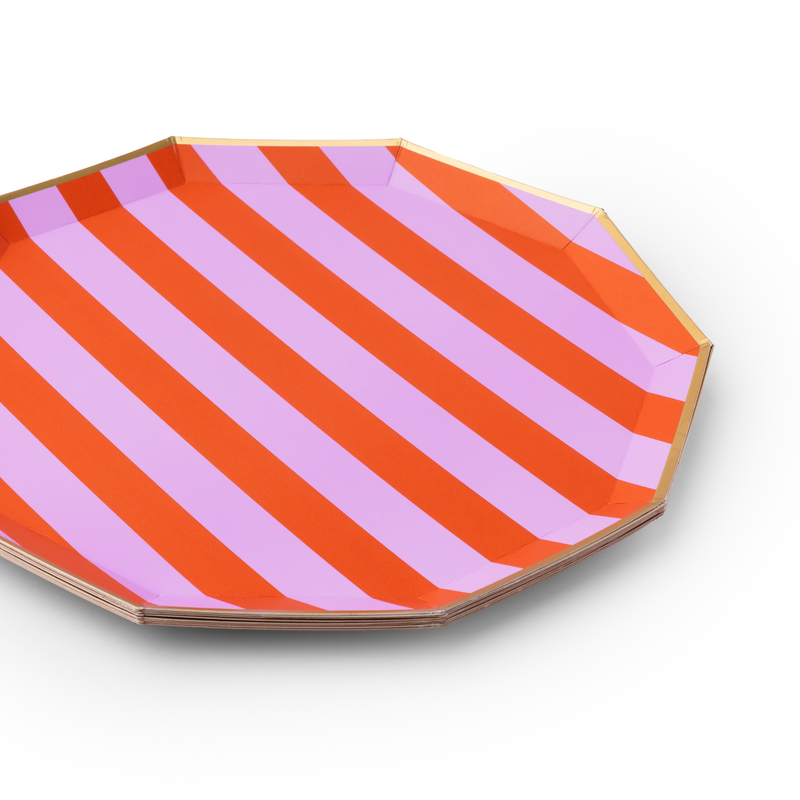 A close-up angled view of an octagonal paper plate featuring diagonal orange and lilac stripes with a thin gold rim.