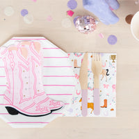 Close-up of the pink boot-shaped napkin on a pink-and-white striped octagon plate, next to a wood-handled fork and horse-print napkin—ready for a cowgirl’s big day.
