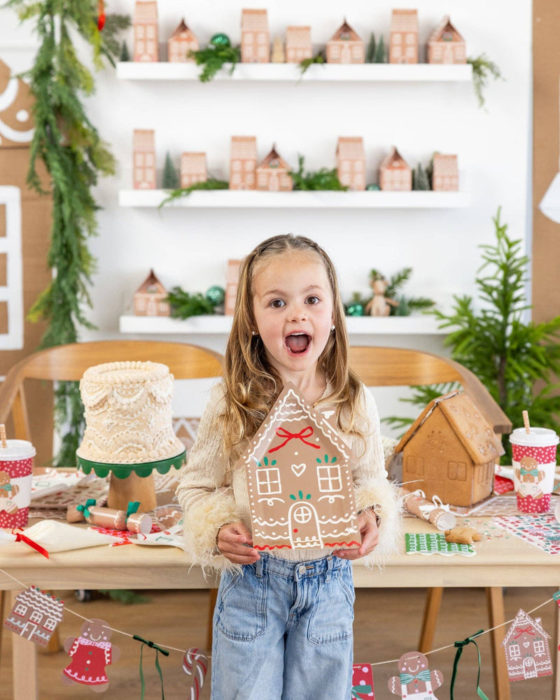 Excited child holding a Ginger House Plate with holiday decorations in the background.