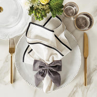Gray velvet bow napkin rings on a crisp white napkin.