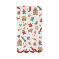 Flat lay of an unfolded Gingerbread Pattern Dinner Napkin featuring gingerbread houses, cookies, and candy canes with a red scalloped edge.